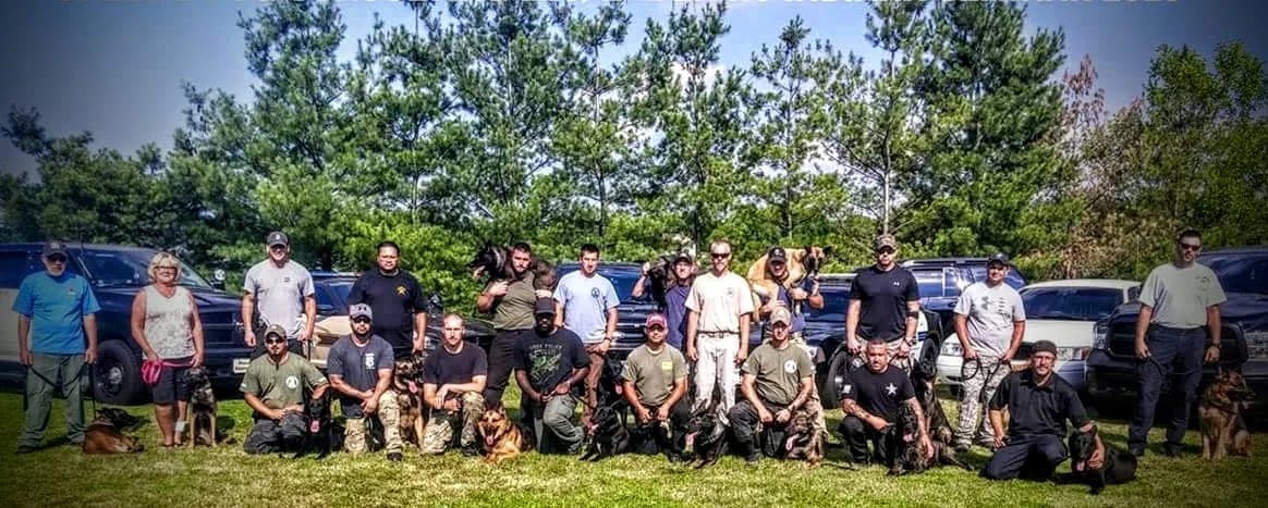 A large group of handlers and their dogs lined up outside at a seminar